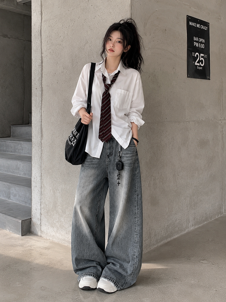 Woman in a white shirt and baggy jeans with a striped tie and high ponytail