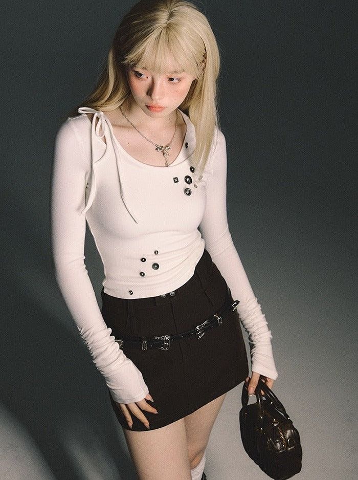 Blonde woman in a white long-sleeve top and black mini skirt holding a small bag