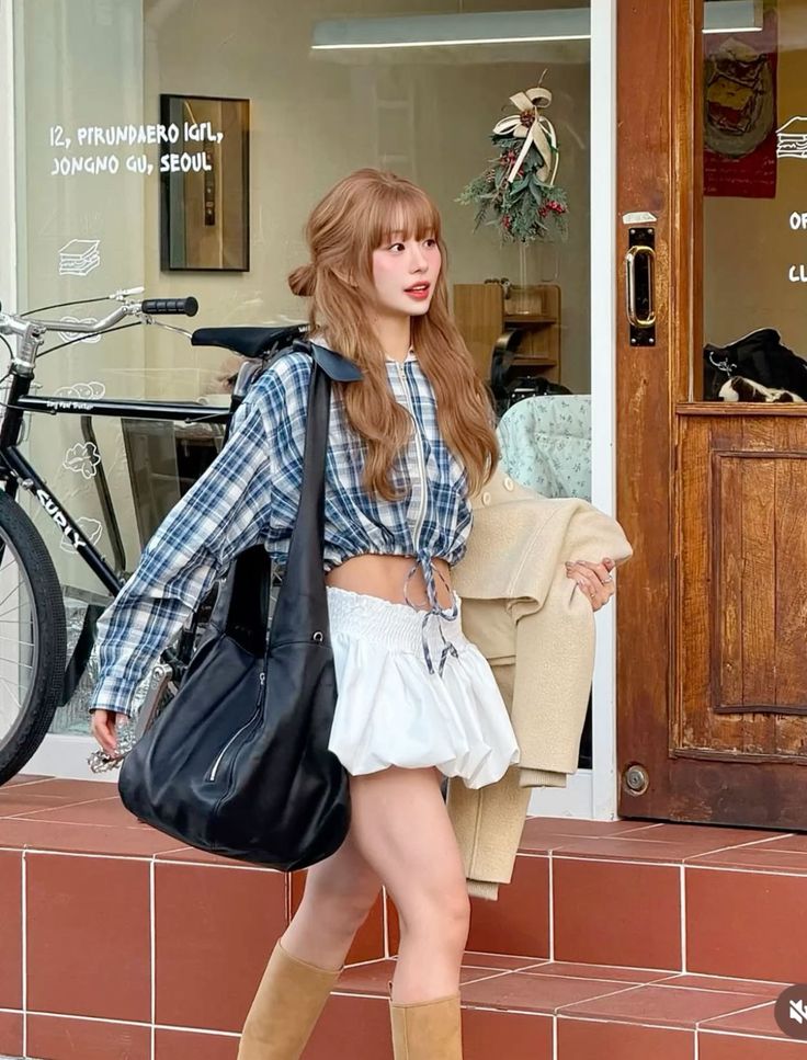 Woman in a plaid crop top and white skirt walking outdoors