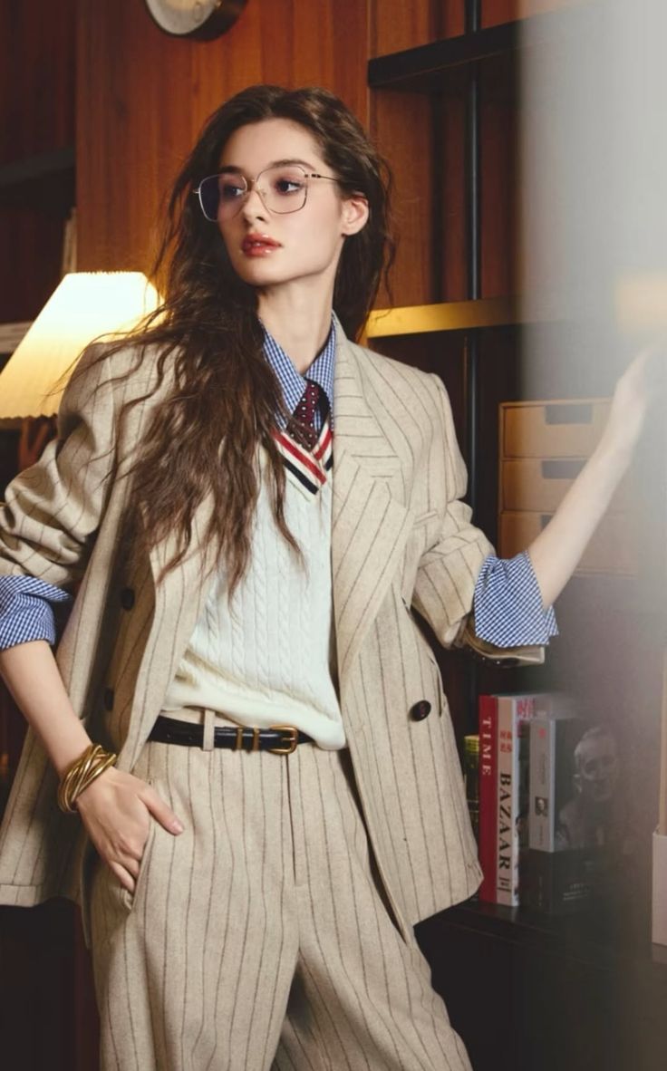 Woman in a pinstripe suit and glasses indoors with soft lighting