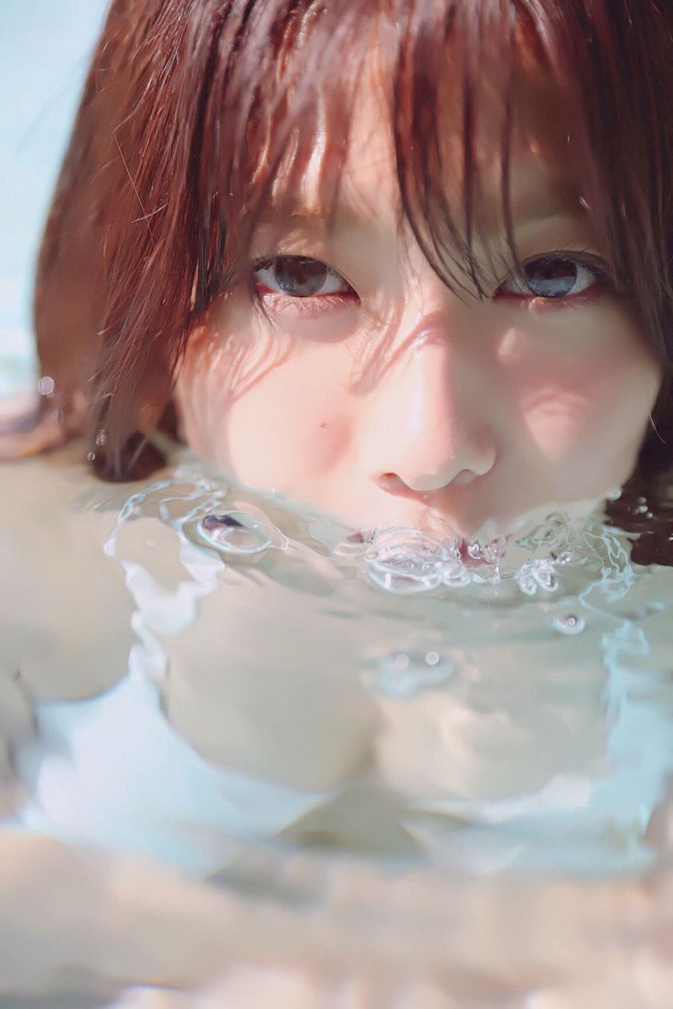 Woman with wet brown hair and cleavage visible in water with bubbles