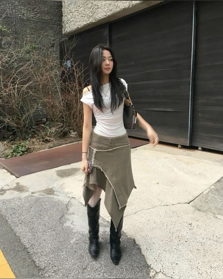 Woman with long black hair wearing an asymmetrical skirt and black boots outdoors