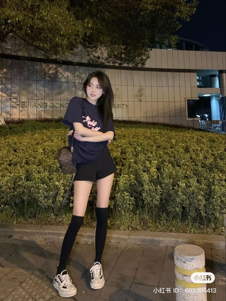 Woman in a dark t-shirt and shorts with knee-high socks at night