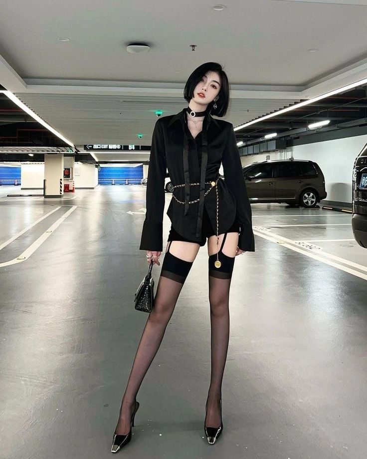 Woman in a black outfit with stockings and high heels in a parking garage