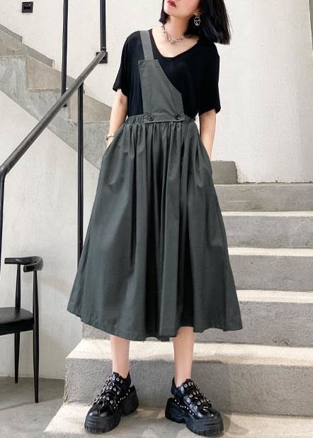 Woman in a black t-shirt and dark grey overalls dress standing on stairs