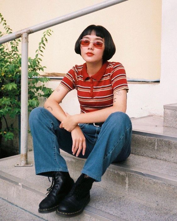 Person with short bob hair and red sunglasses sitting on outdoor steps