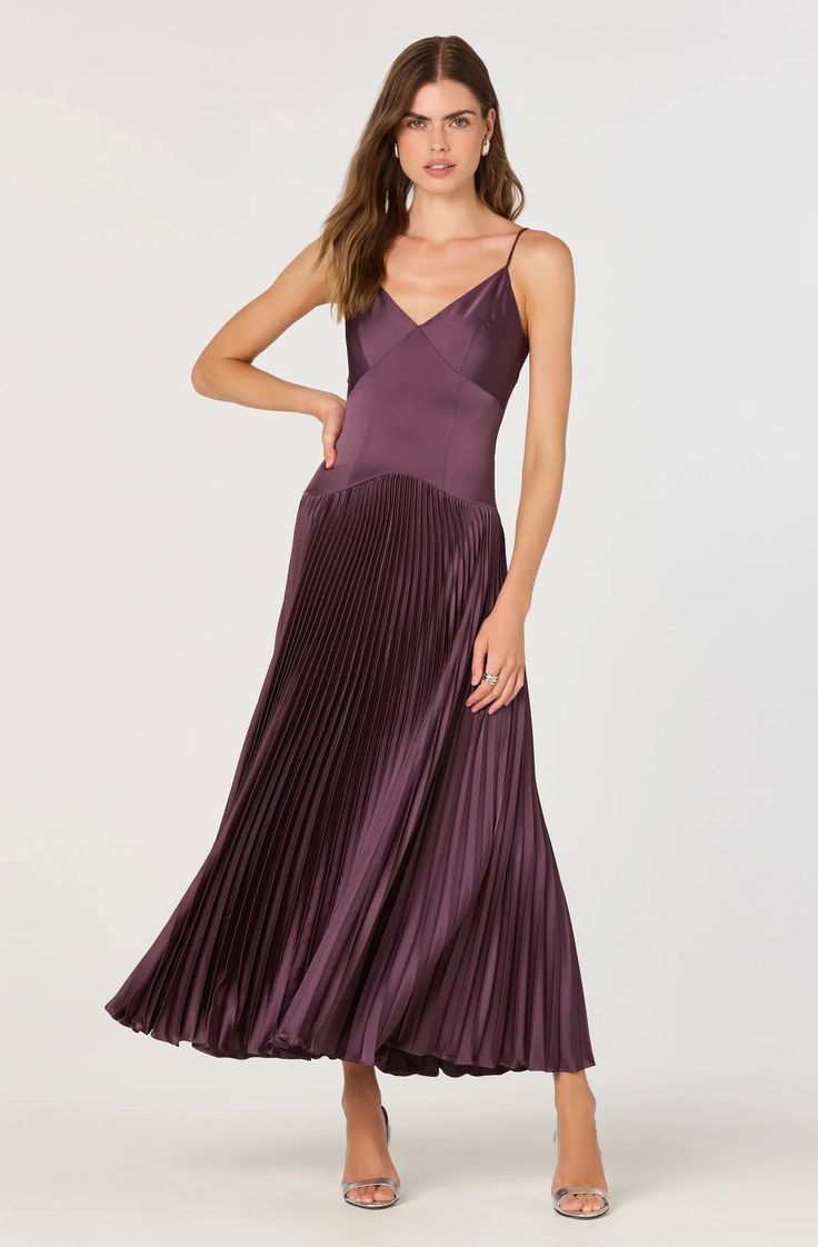 Woman in a purple pleated dress and high heels posing in a studio