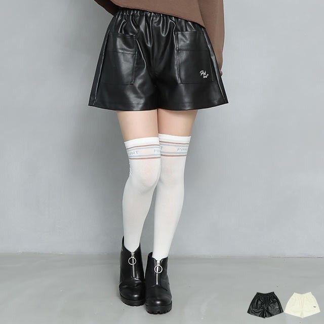 Person wearing black leather shorts, white thigh-high socks, and black boots