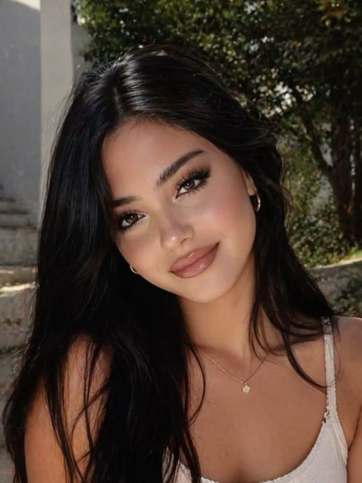 Woman with long black hair and natural makeup outdoors