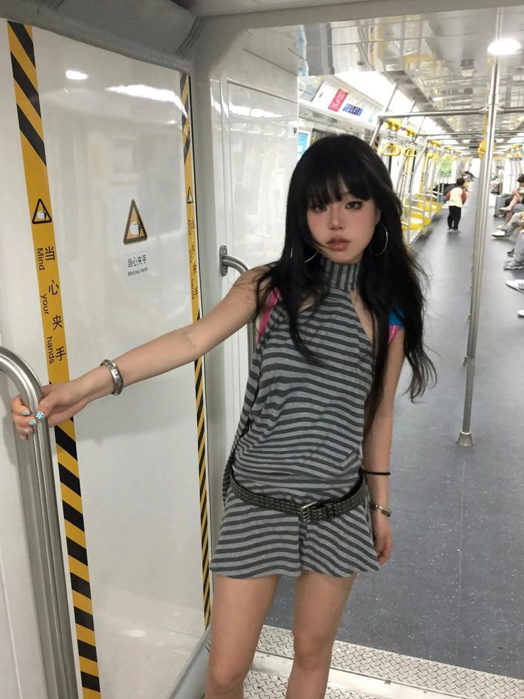 Woman with long black hair and a striped dress in a subway car