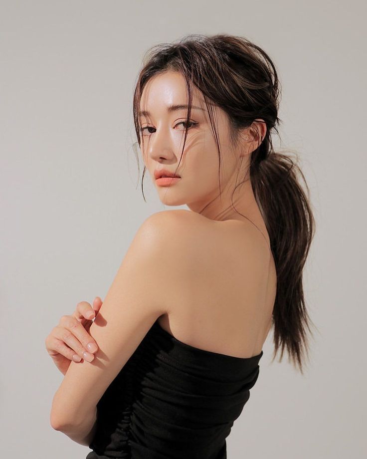 Woman with a ponytail wearing a strapless top, looking over her shoulder
