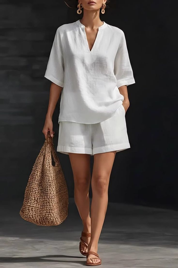 Woman in a white linen shorts and blouse set, holding a straw bag
