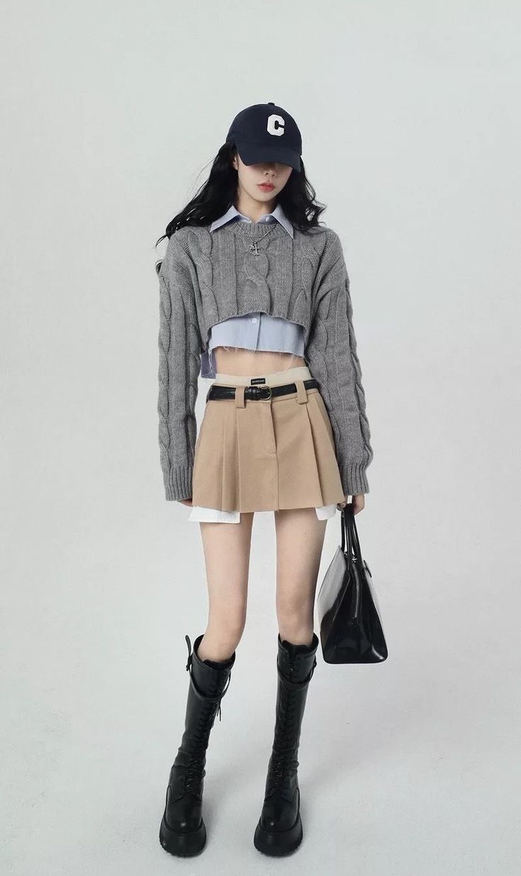 Woman in a cropped sweater, mini skirt, and knee-high boots with a baseball cap