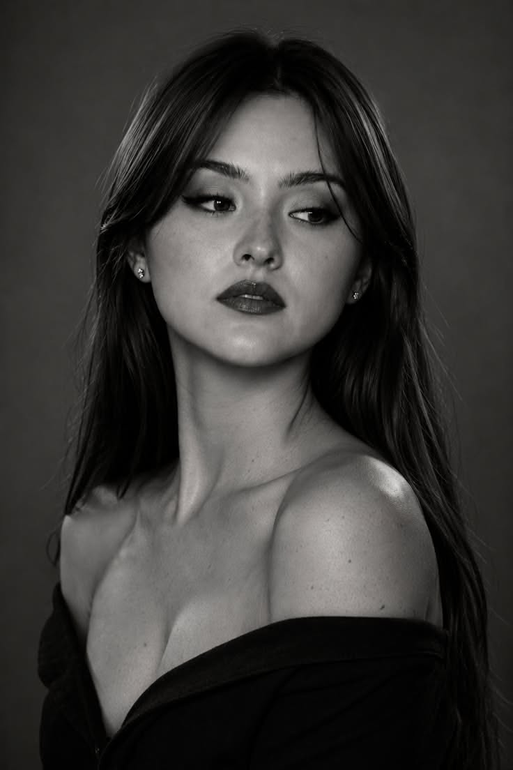 Woman with long dark hair and an off-shoulder top in a black and white portrait