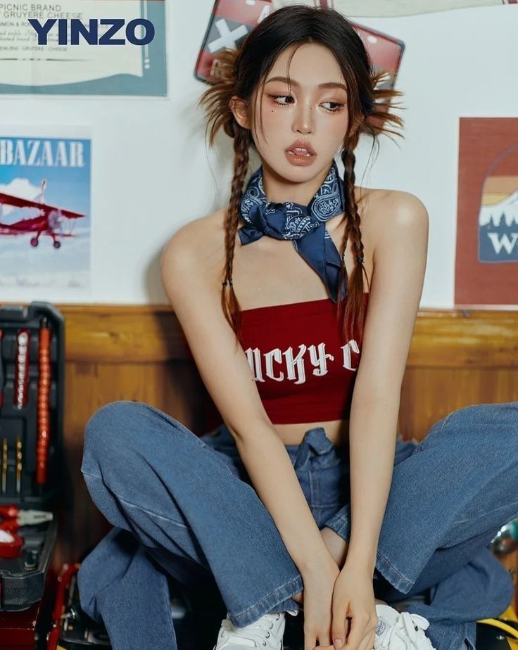 Woman with braids and a bandana wearing a red crop top and blue jeans