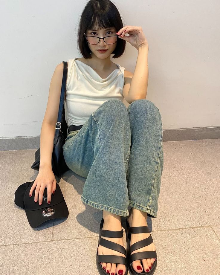 Woman with short hair and glasses sitting on the floor indoors