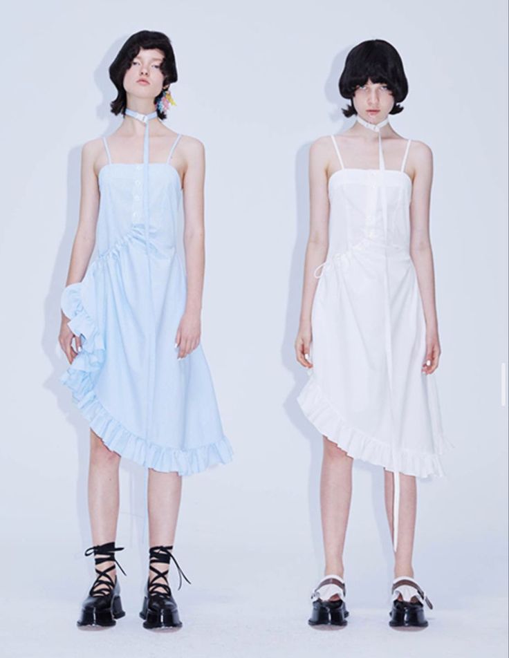 Two models in light blue and white ruffle dresses with chokers and black shoes