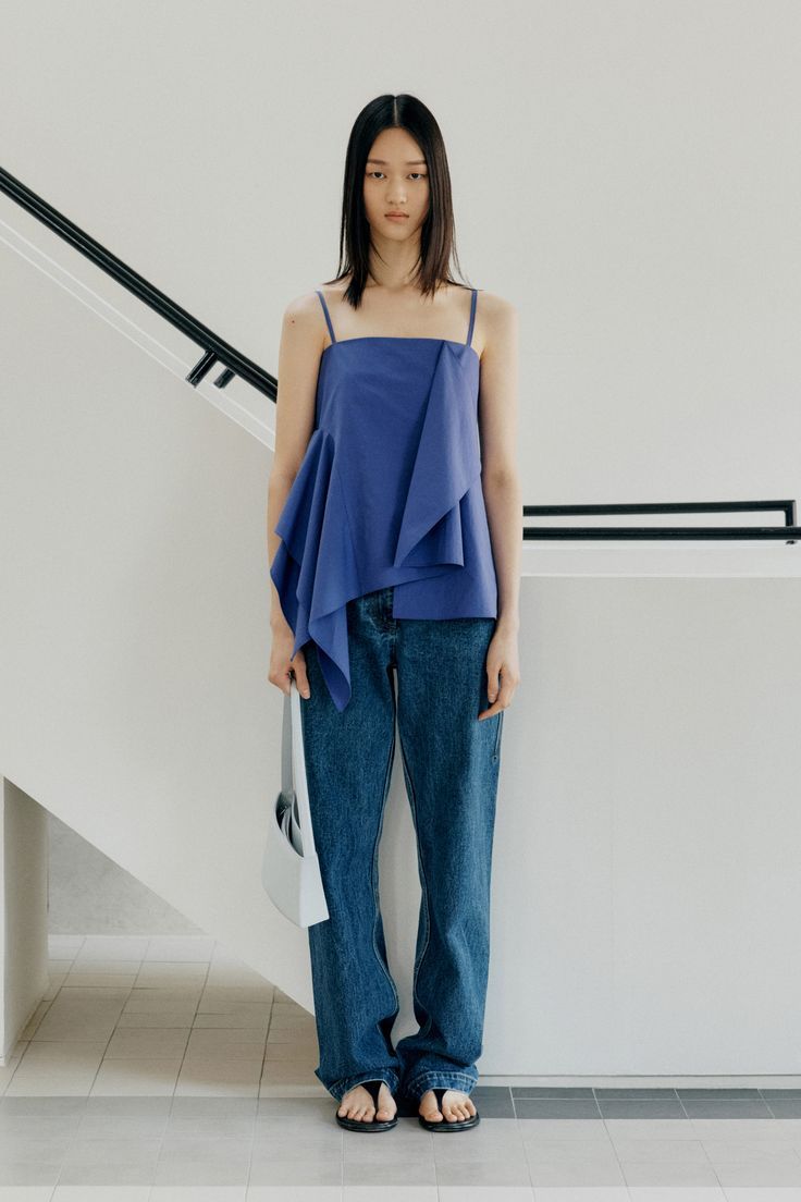 Woman in a blue top and denim jeans standing indoors
