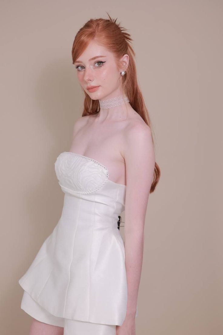 Woman with red hair wearing a white strapless dress and lace choker