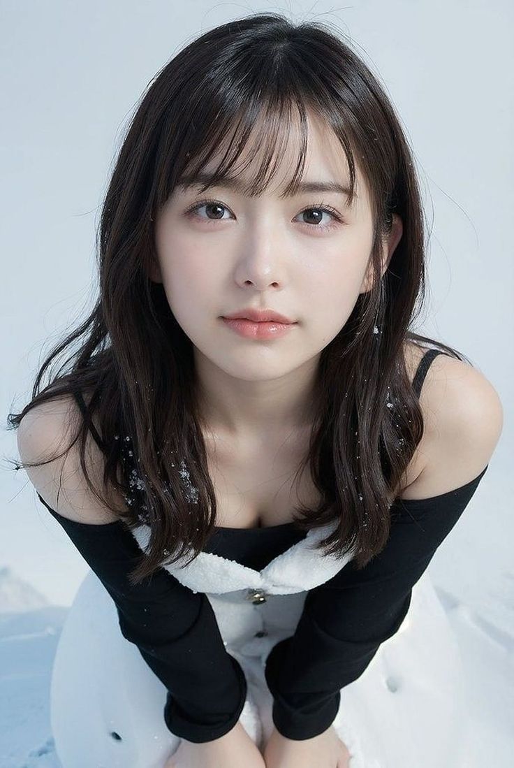Woman with long black hair and bangs in a black top and white dress in snow