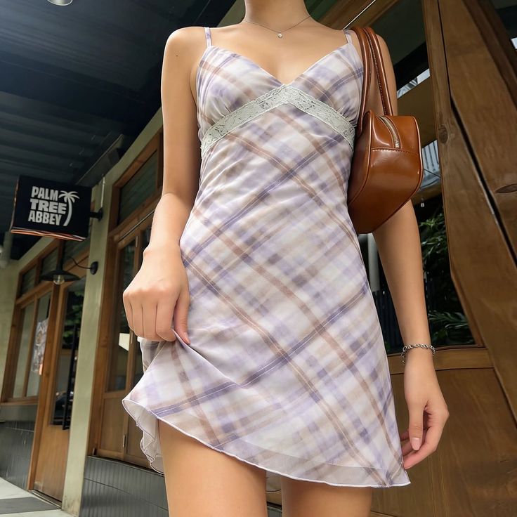 Woman in a plaid mini dress with a brown handbag outdoors