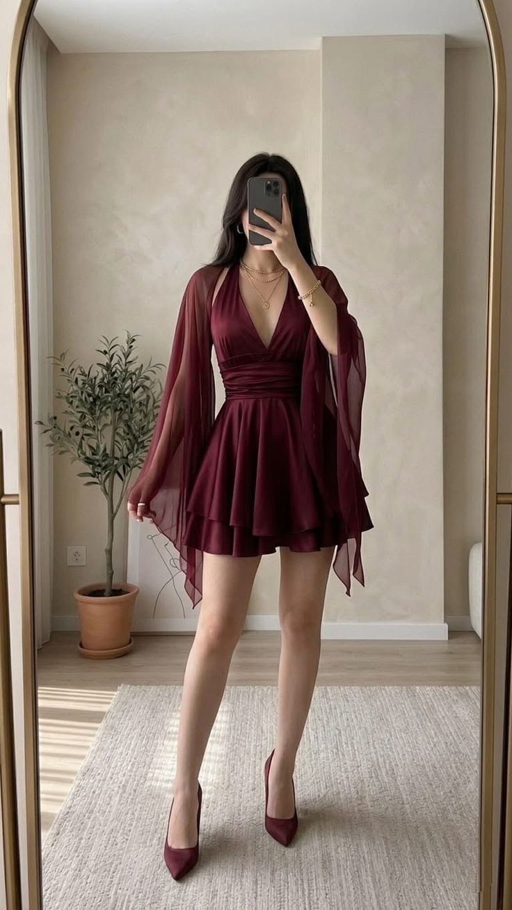 Woman in a burgundy dress and high heels taking a mirror selfie