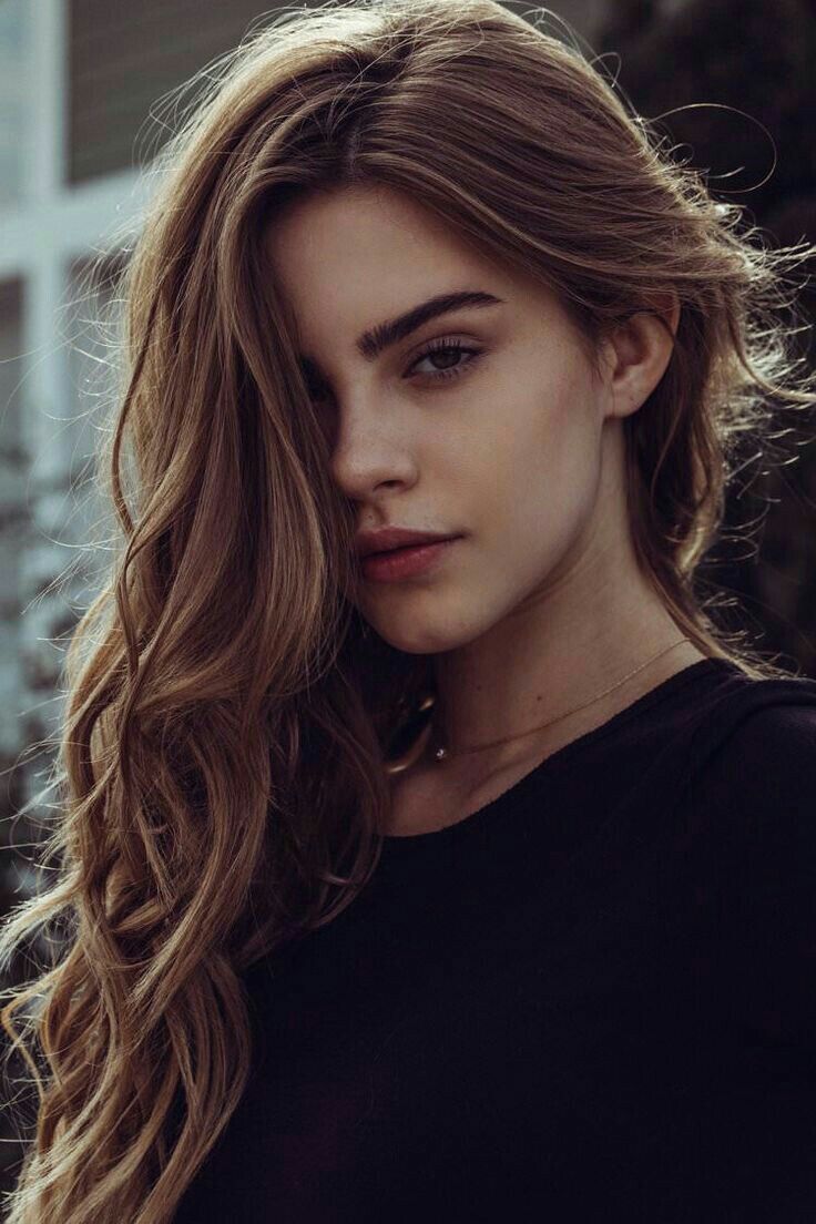 Woman with long wavy hair and a dark top looking directly at the viewer