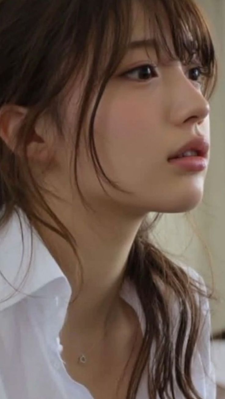 Woman with long brown hair in a white shirt looking to the side