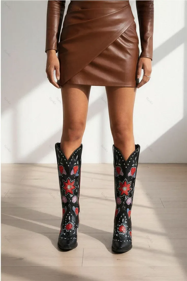 Person wearing a brown leather skirt and black embroidered cowboy boots