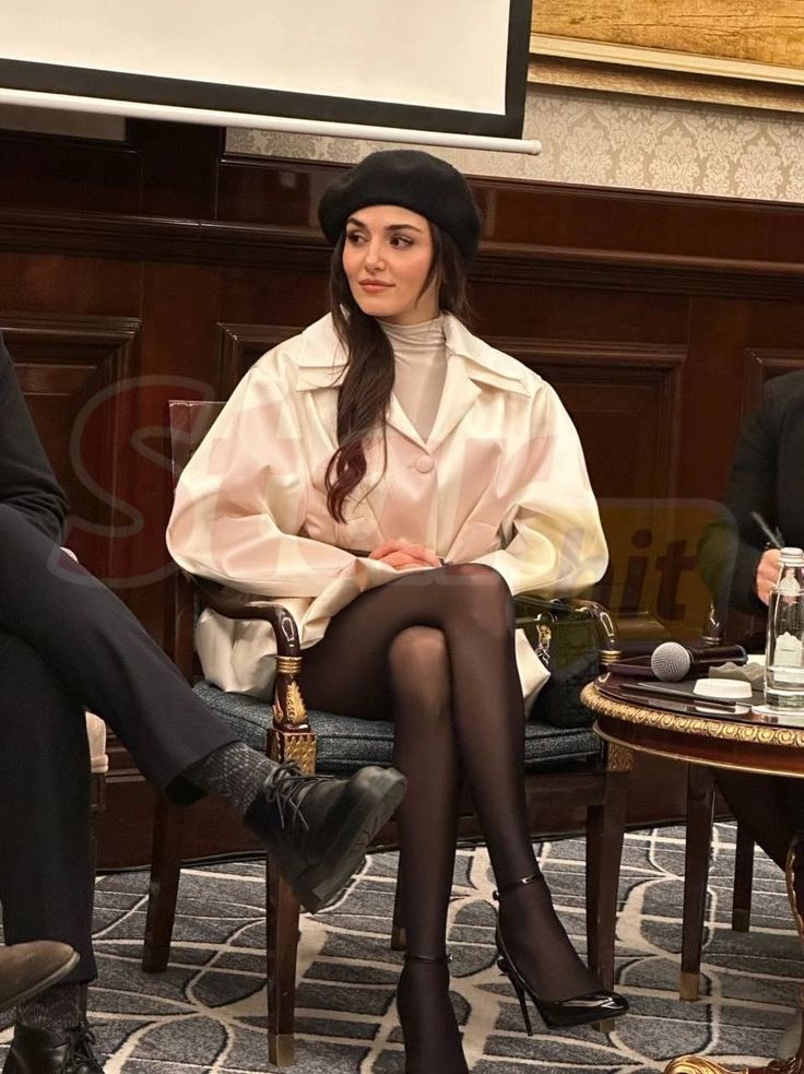 Woman in a black beret and white shirt sitting indoors