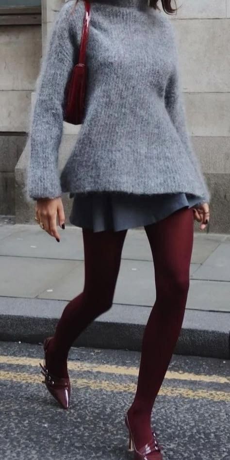 Person in a gray sweater, mini skirt, and red tights walking on a street