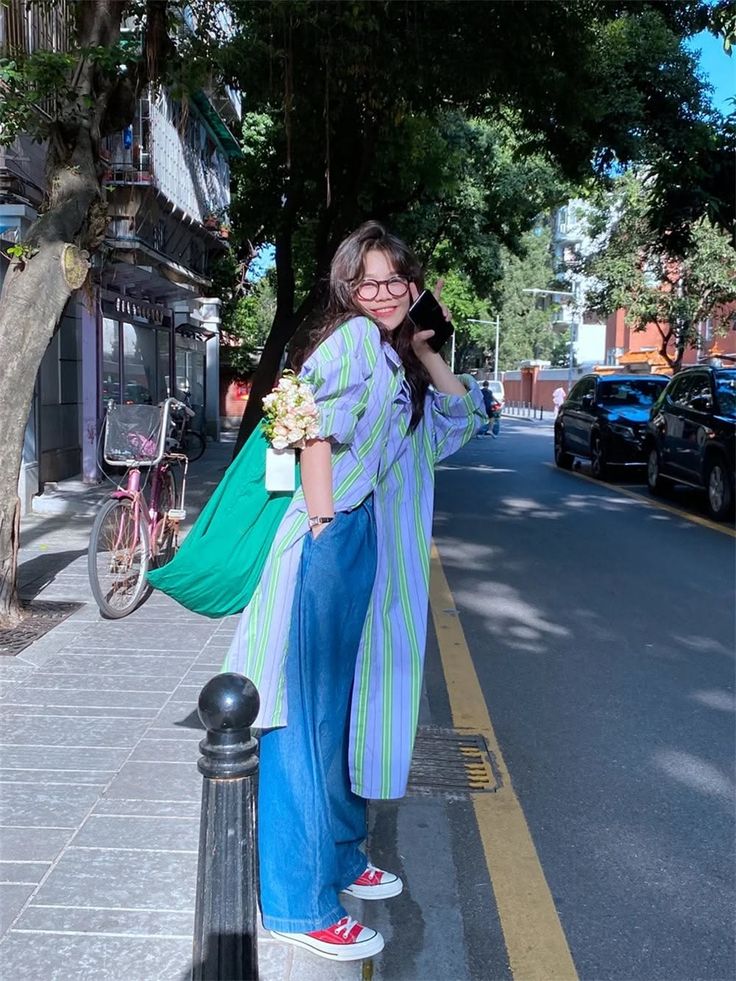 Woman in a striped shirt and wide leg jeans standing on a sunny street