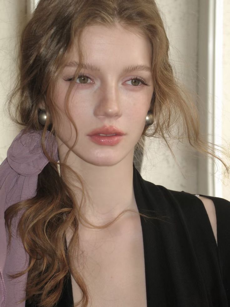 Woman with long wavy hair and natural makeup wearing a black top