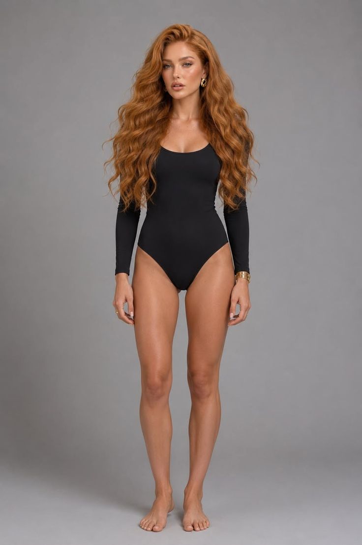 Woman with long red wavy hair in a black bodysuit standing barefoot