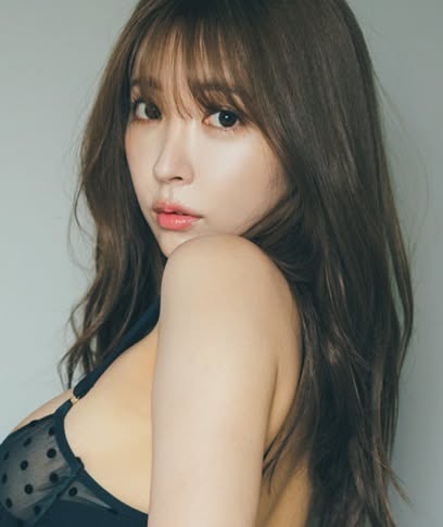 Woman with long hair wearing a black polka dot bra, looking over her shoulder