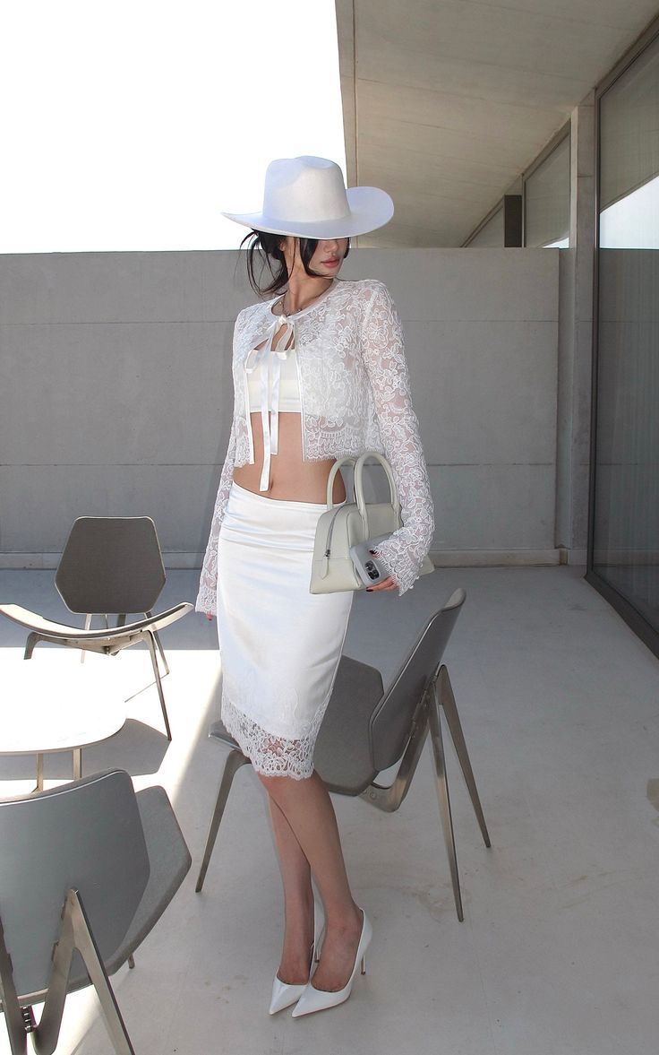 Woman in a white lace outfit and hat posing outdoors