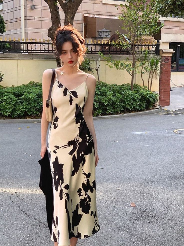 Woman in a floral slip dress standing on a street with soft lighting