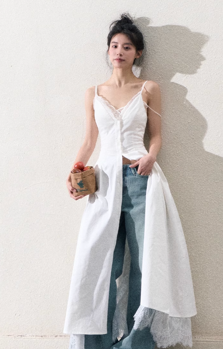 Woman in a white dress over jeans holding a small bag of apples