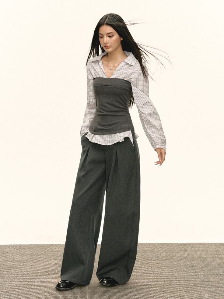 Woman with long dark hair wearing a plaid shirt and wide leg pants