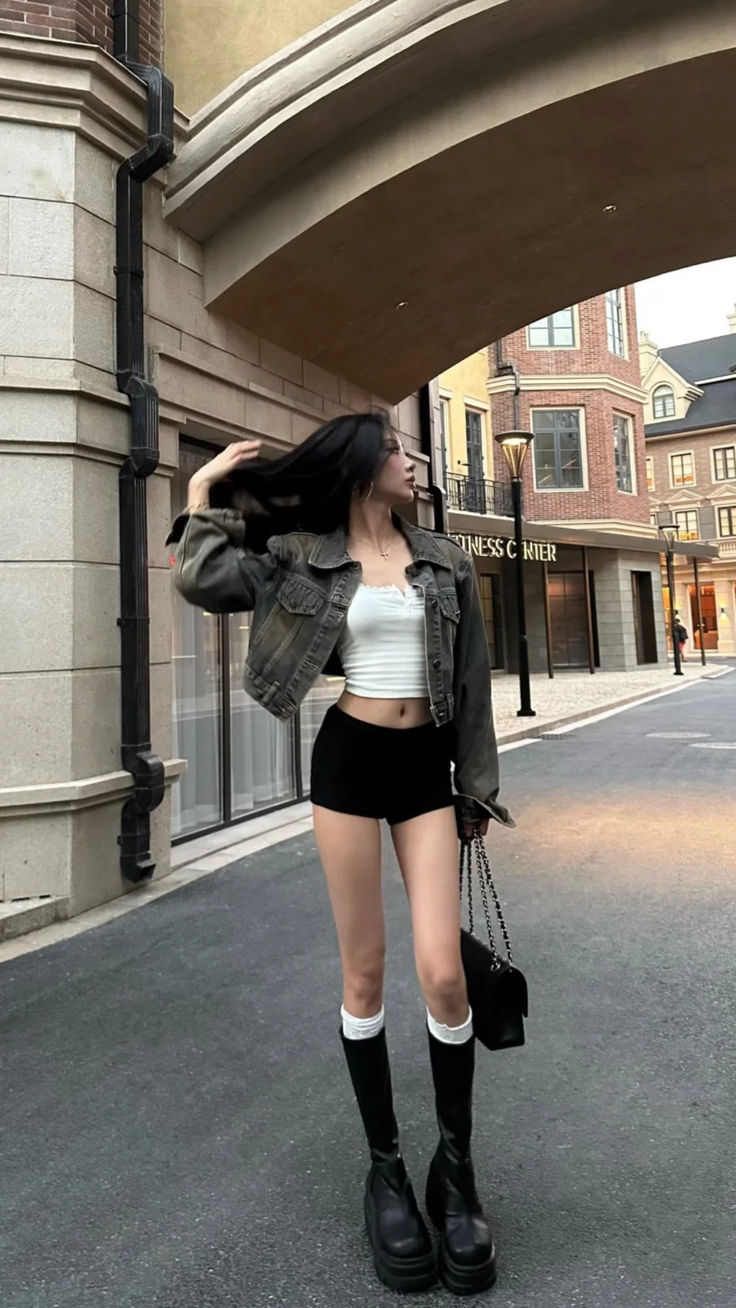 Woman in a crop top and shorts with a denim jacket on a street
