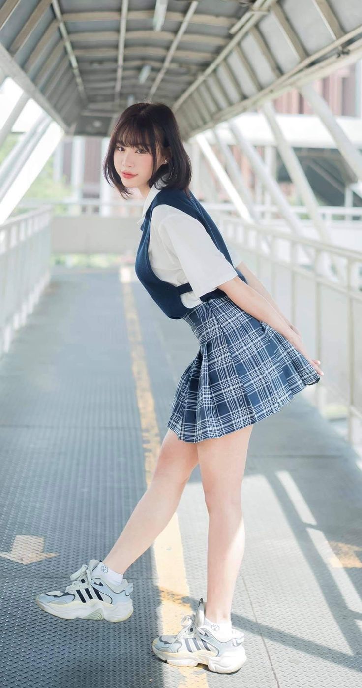 Woman in a school uniform posing on an outdoor walkway