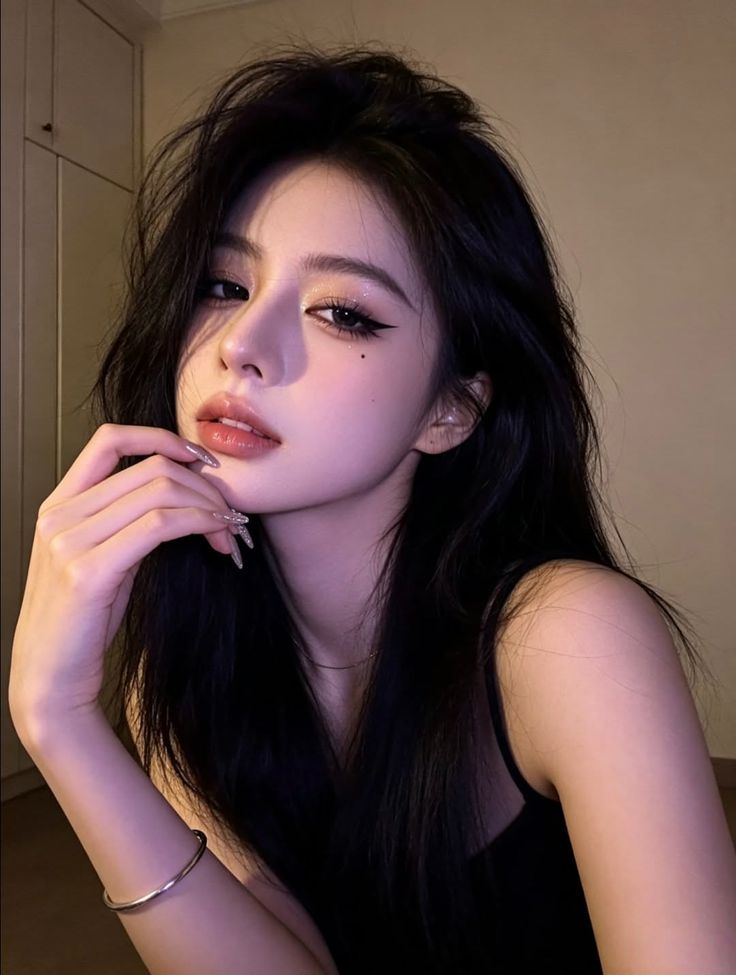 Woman with long black hair and dramatic makeup in a black top