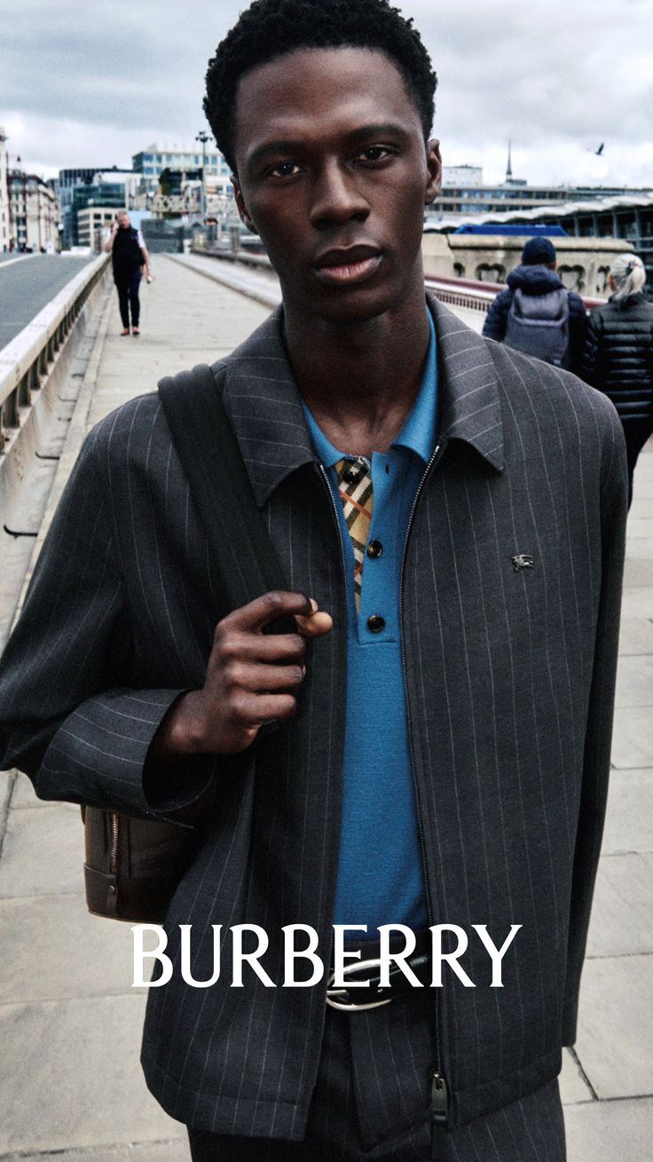 Man in a pinstripe jacket and blue polo shirt on a street