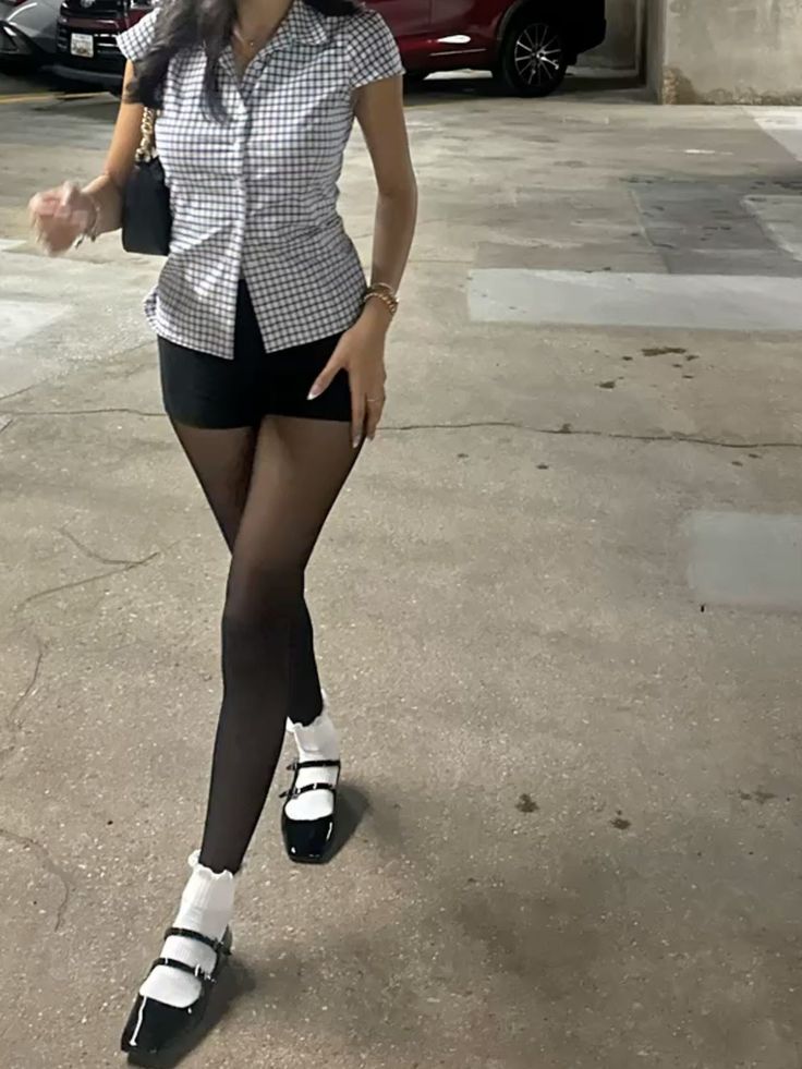 Person in a plaid shirt, black shorts, and tights with mary jane shoes