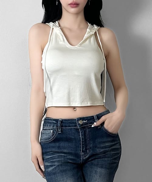 Woman in a white crop top and dark wash jeans with a belly button piercing