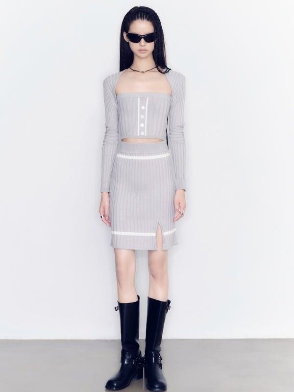 Woman in a gray ribbed knit crop top and mini skirt with black boots and sunglasses