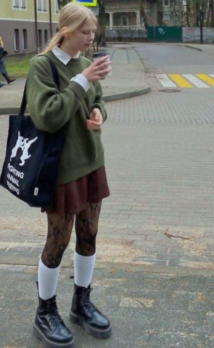 Young woman with blonde hair in a green sweater and brown skirt on a street
