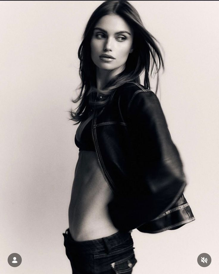 Woman in a leather jacket and bra with exposed midriff in a studio shot