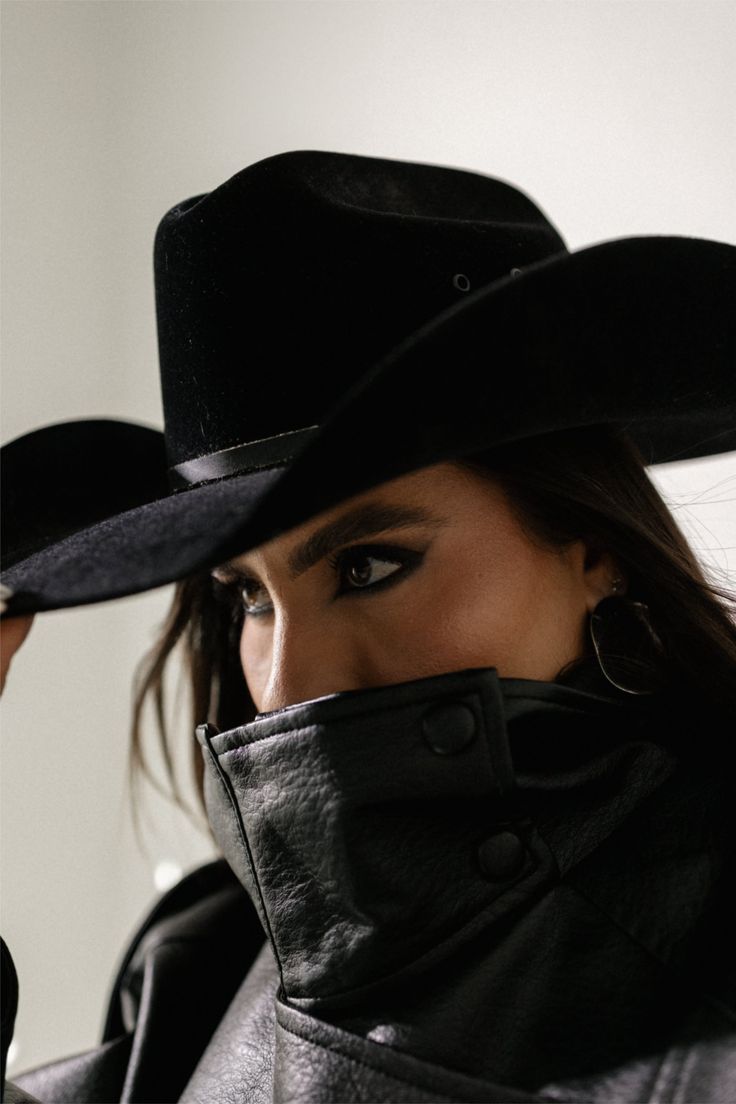 Woman in a black cowboy hat and leather jacket with dark eye makeup