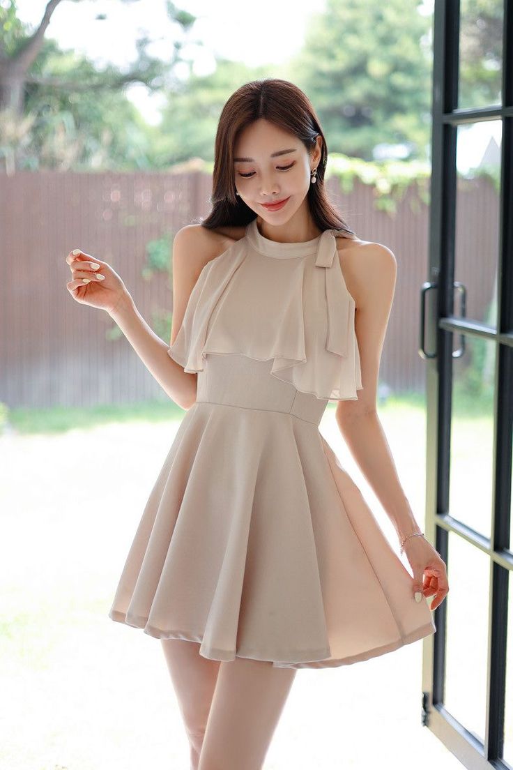 Woman in a short beige ruffle dress standing outdoors